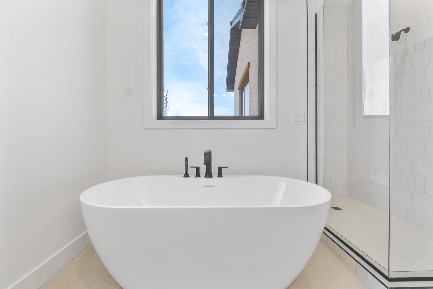 Freestanding soaking tub with window and elegant tile shower surround — luxury bath Rexburg